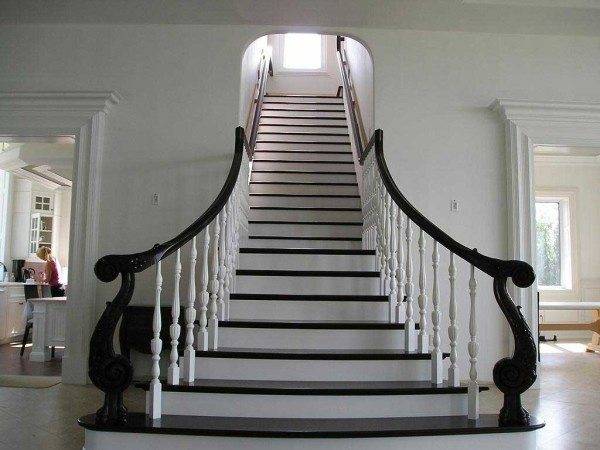 La photo montre une élégante structure de marche avec des contremarches blanches, des balustres et des balustrades noires