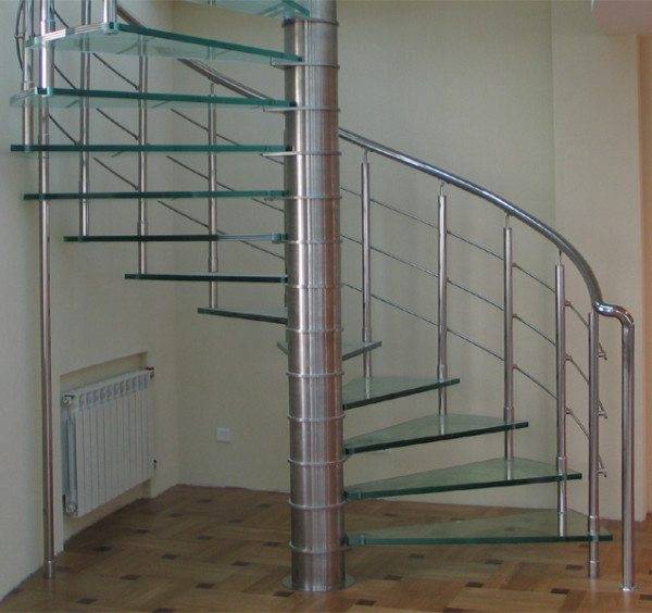 A képen egy csiga nyitott lépcső látható, üveg lépcsőkkel és fém korlátokkal.